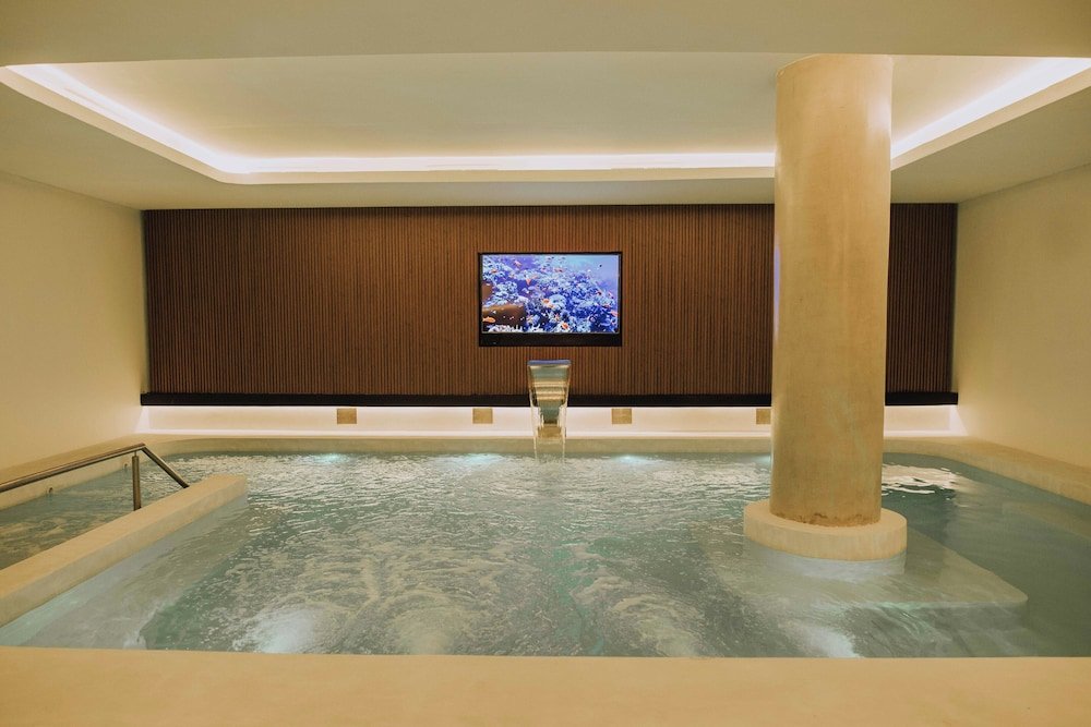 Sector de spa con hidromasaje grande, paneles de madera y televisor