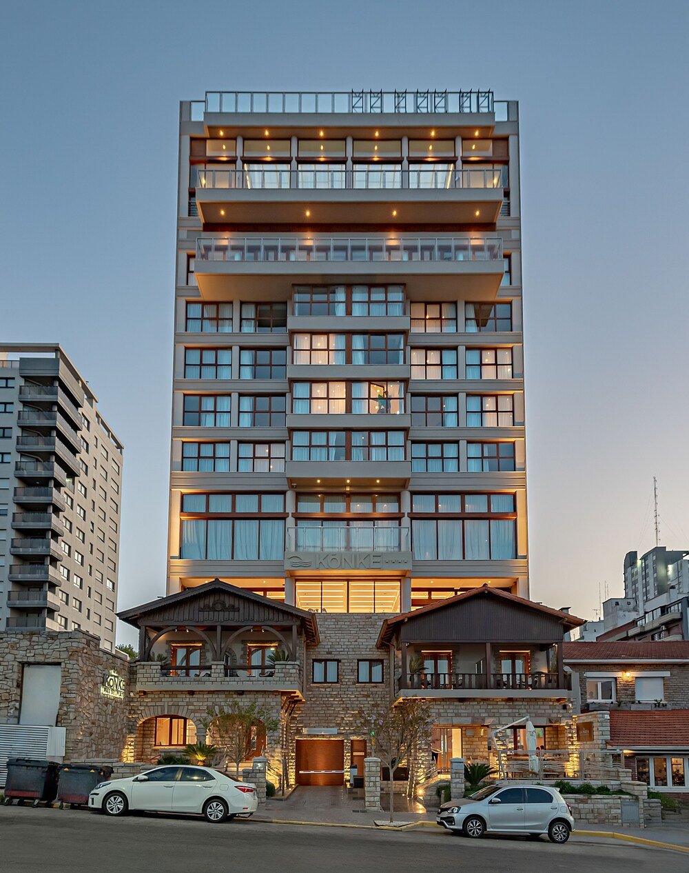 Fachada moderna de varios pisos con balcones, ventanales y piedra