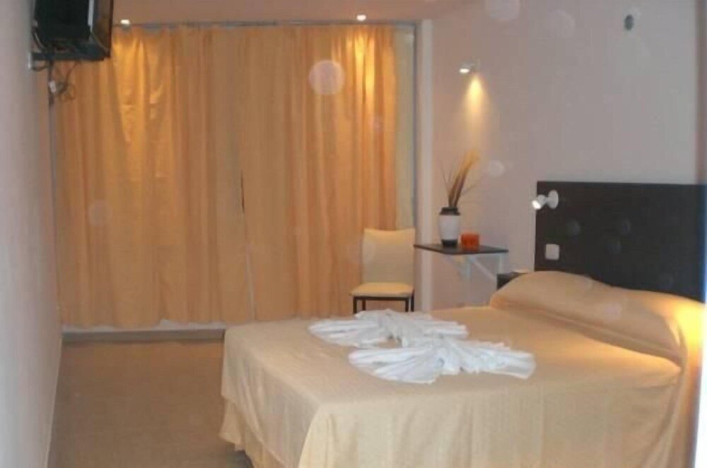 Habitación del hotel con cama matrimonial y una silla junto a la ventana