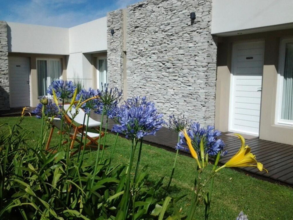 Edificio moderno de paredes de piedra con césped y flores